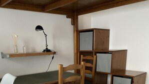 Puisesta pöydästä, tuolista, lampusta ja koriste-esineillä varustetusta hyllystä koostuva työpiste.