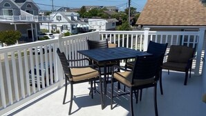 A covered outdoor patio with a table and chairs, surrounded by a white fence.
