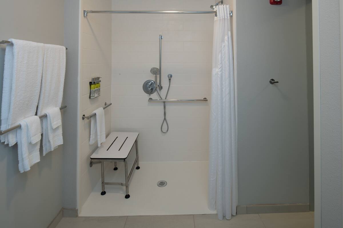 A bathroom with a shower, a towel rack, and a small table.