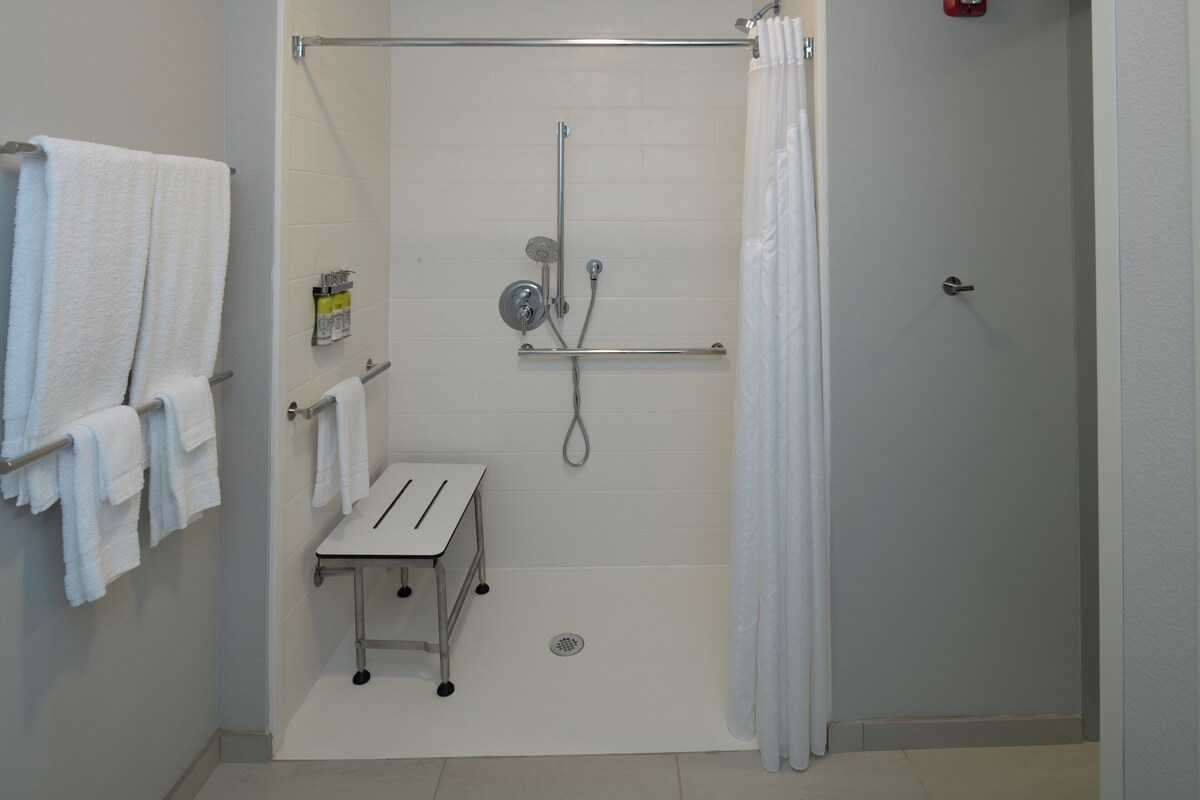 Een badkamer met een douche, een handdoekhouder en een klein tafeltje.