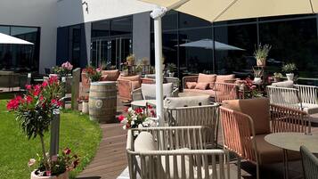 An outdoor seating area with wicker furniture, potted plants, and a wooden barrel.