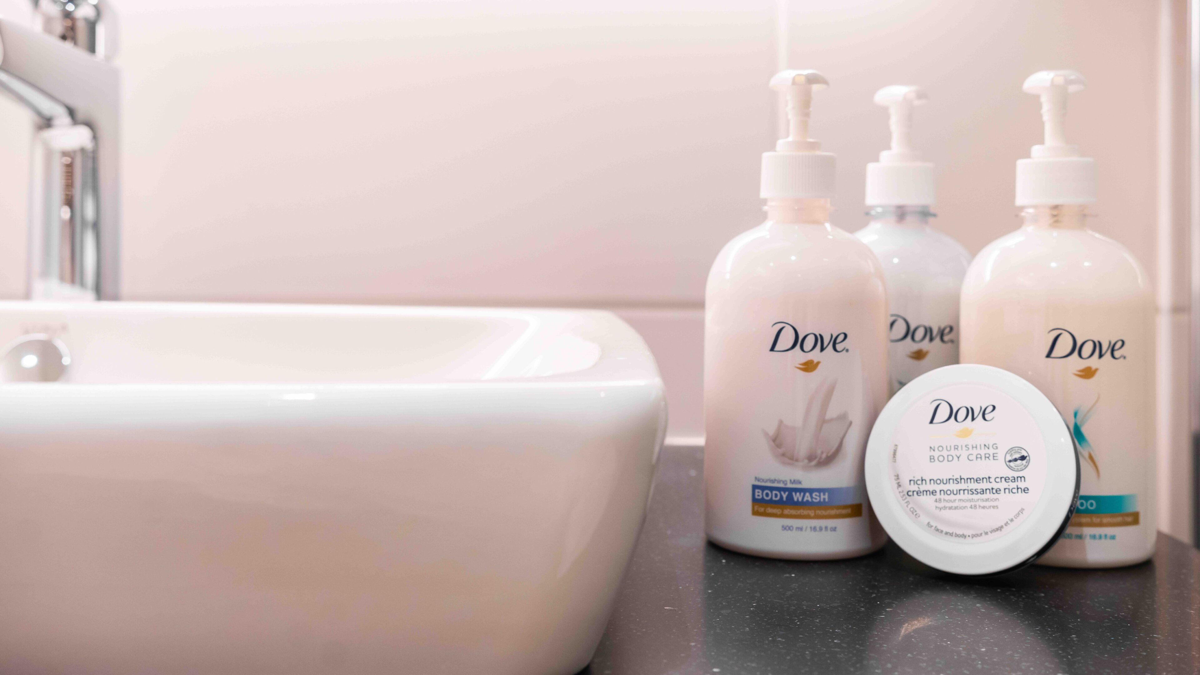 A bathroom sink with Dove body care products.