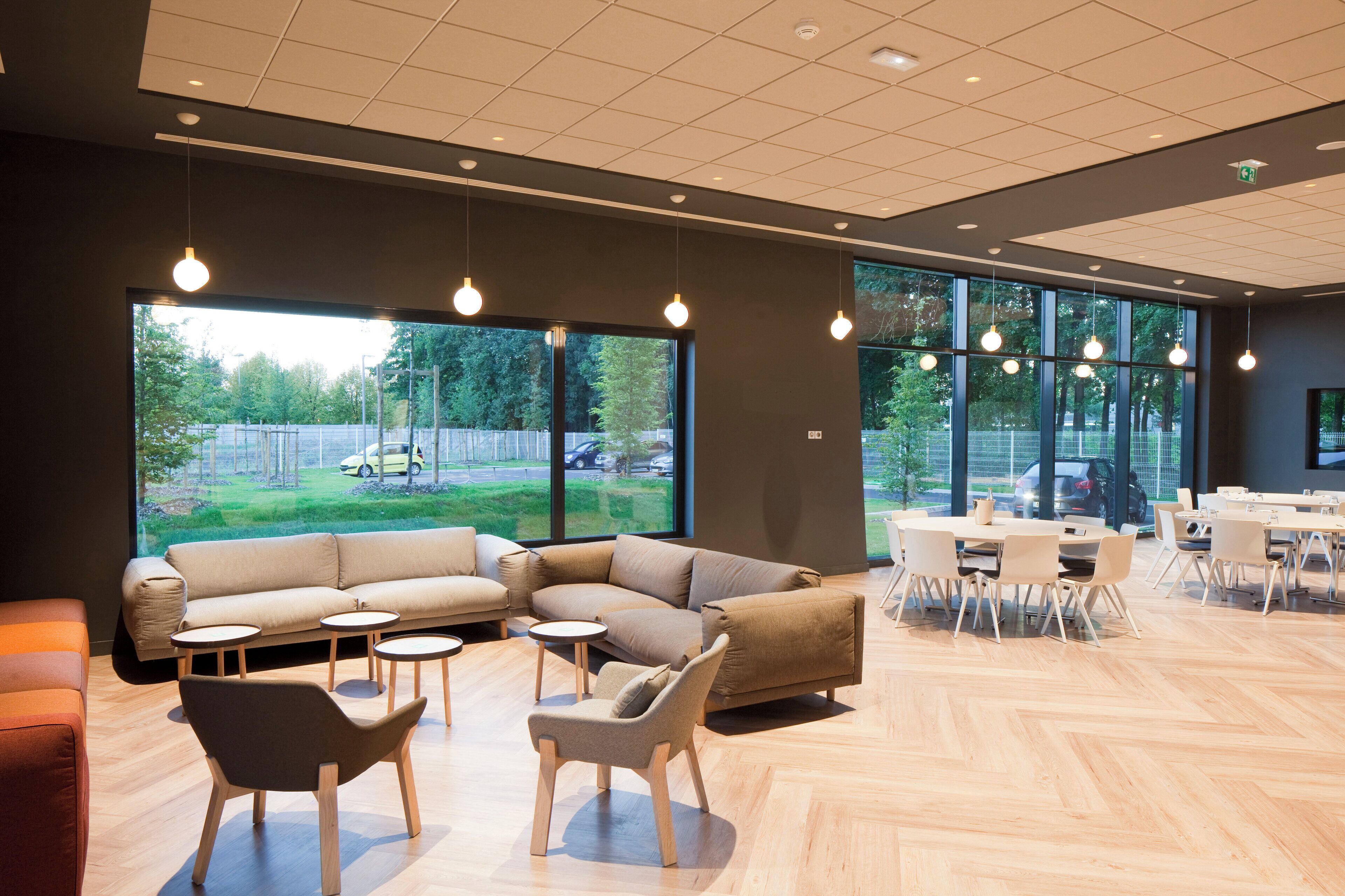 A modern interior with a sectional sofa, round tables, and a dining area.