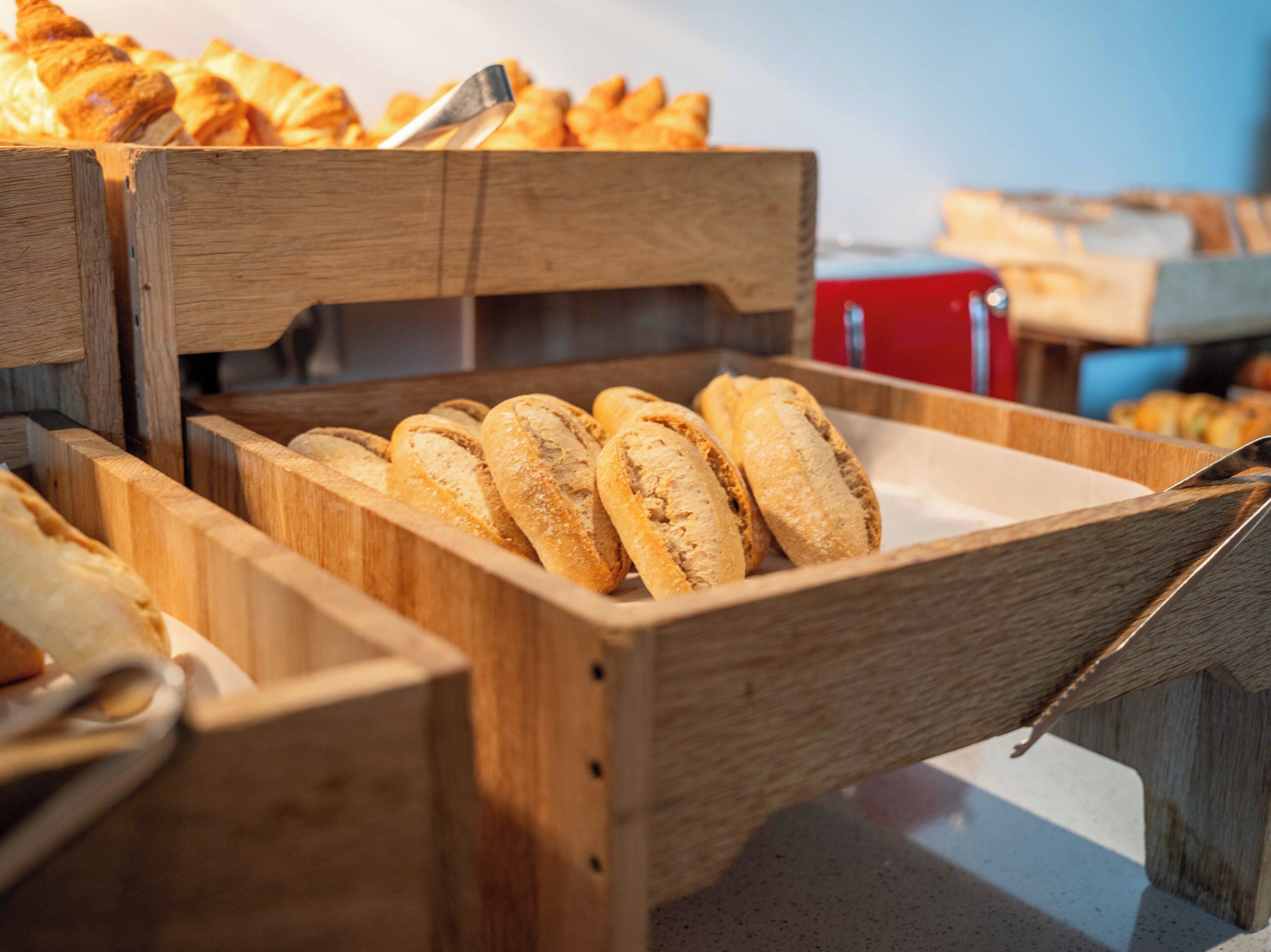 A wooden bread box with several loaves of bread inside.