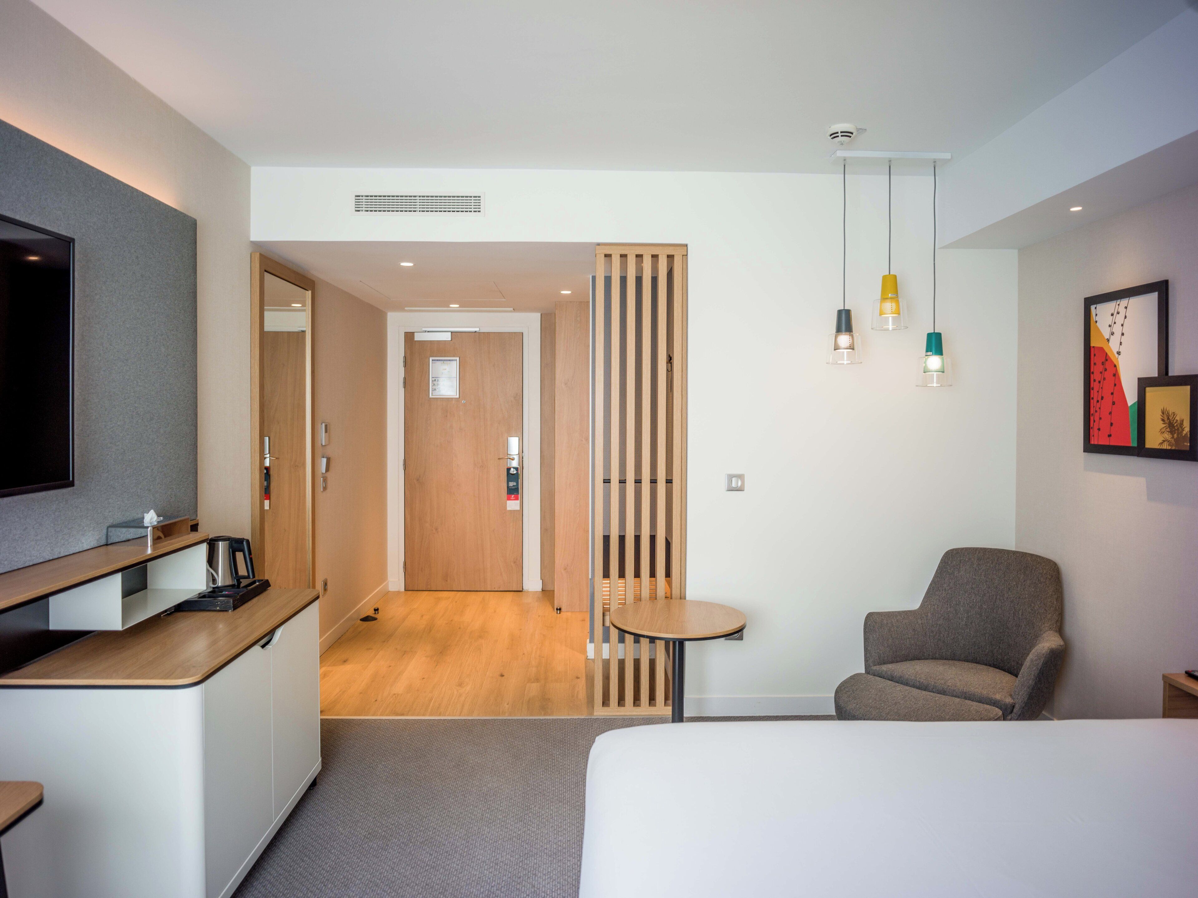 Een hotelkamer met een bed, een bureau, een stoel, een kleine tafel en een televisie.