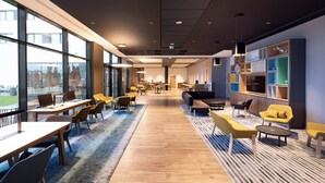 A spacious, modern interior with large windows, wooden flooring, and contemporary furniture. - Holiday Inn Paris CDG Airport by IHG (Roissy-en-France)