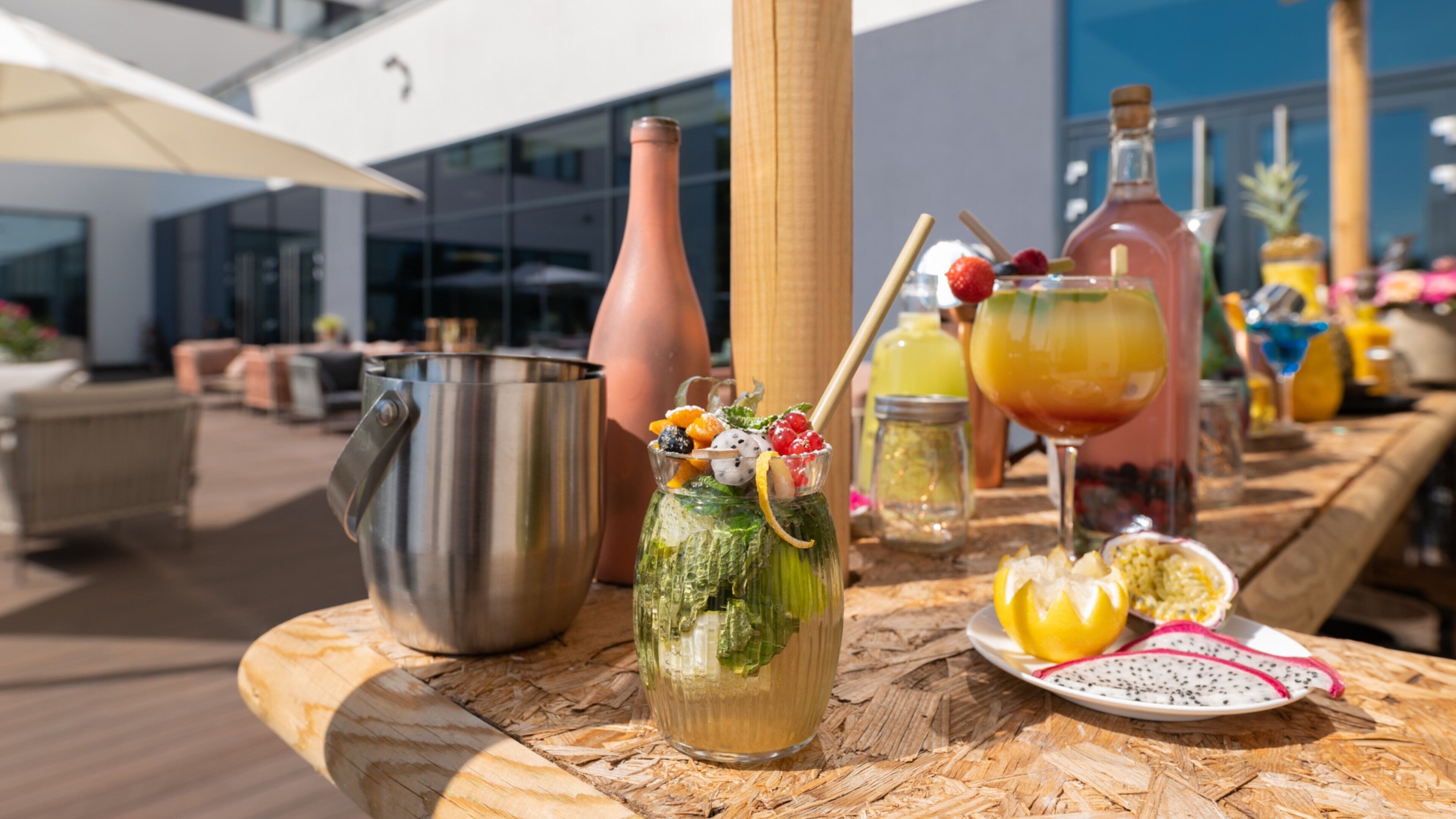 A table with drinks, a metal pitcher, a glass pitcher, and a bottle.