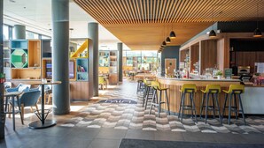 A modern cafe with a bar area, seating, and a patterned floor. - Holiday Inn Paris CDG Airport by IHG (Roissy-en-France)