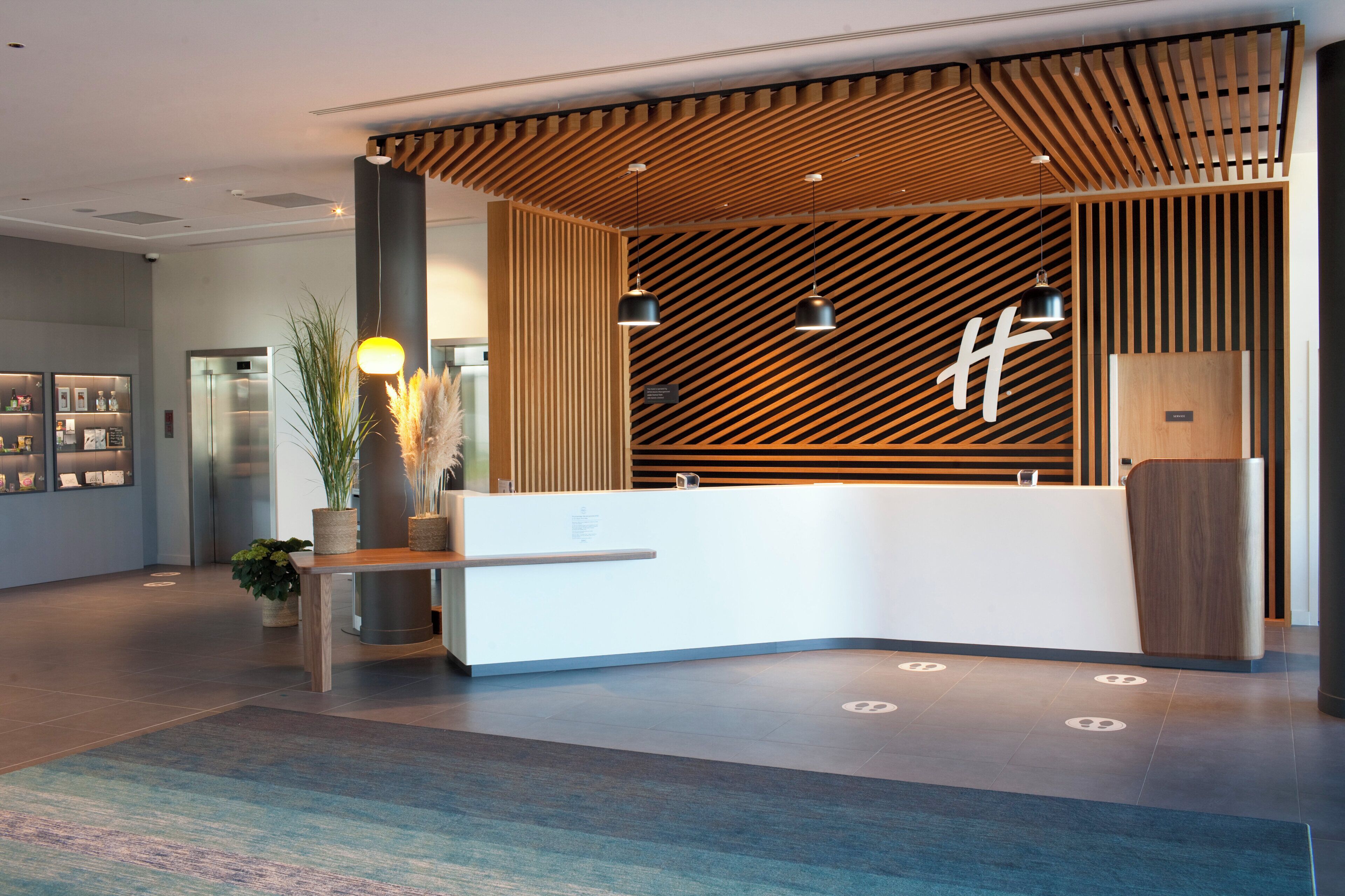 A modern reception area with a wooden slatted wall, a reception desk, and a large logo.