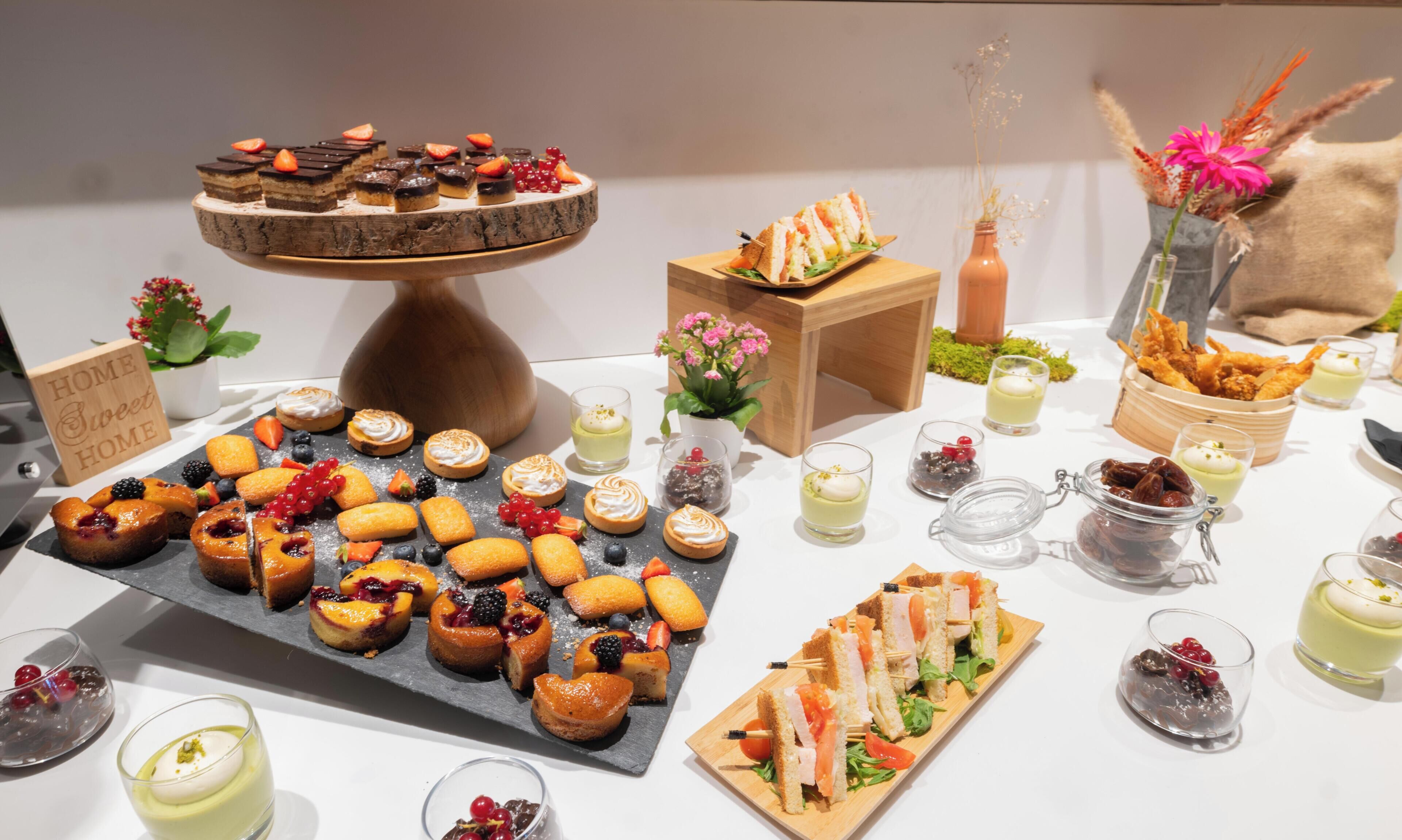 Diverse desserts en snacks, zoals taarten, gebak en sandwiches, gerangschikt op een tafel.