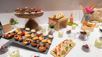 Diverse desserts en snacks, zoals taarten, gebak en sandwiches, gerangschikt op een tafel.