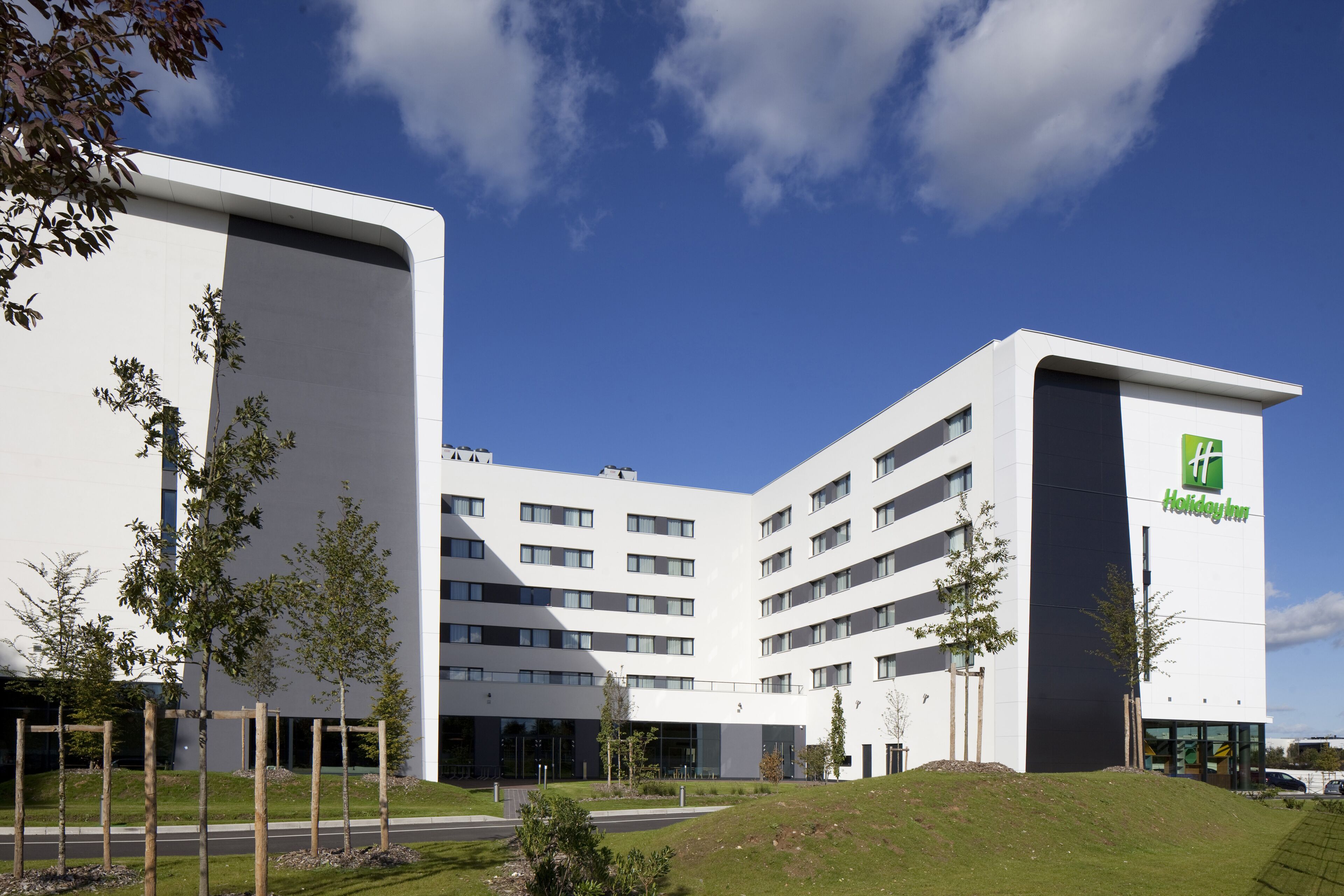 Un hôtel Holiday Inn moderne, avec une façade blanche, plusieurs étages et un toit plat.