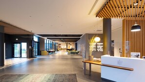 A spacious lobby with a reception desk, seating area, and large windows allowing natural light. - Holiday Inn Paris CDG Airport by IHG (Roissy-en-France)