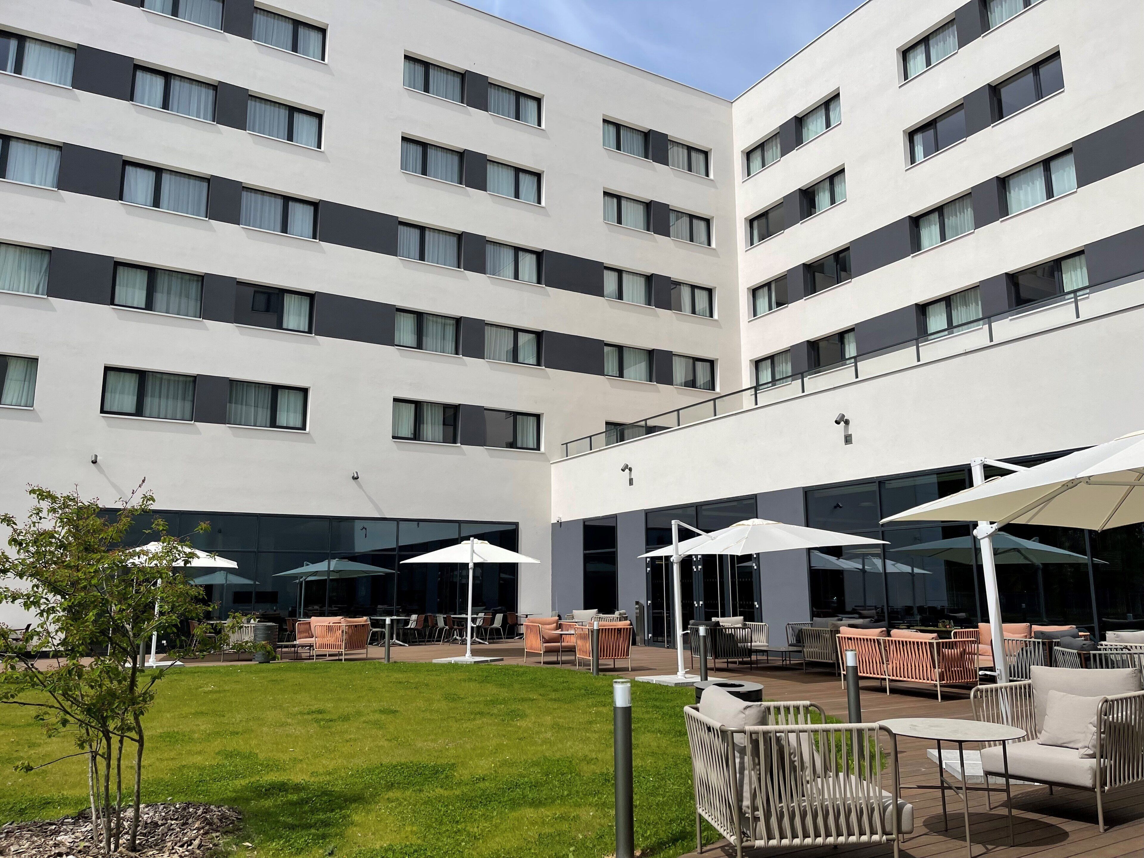 Un hotel moderno con un patio que ofrece asientos al aire libre y un césped bien cuidado.