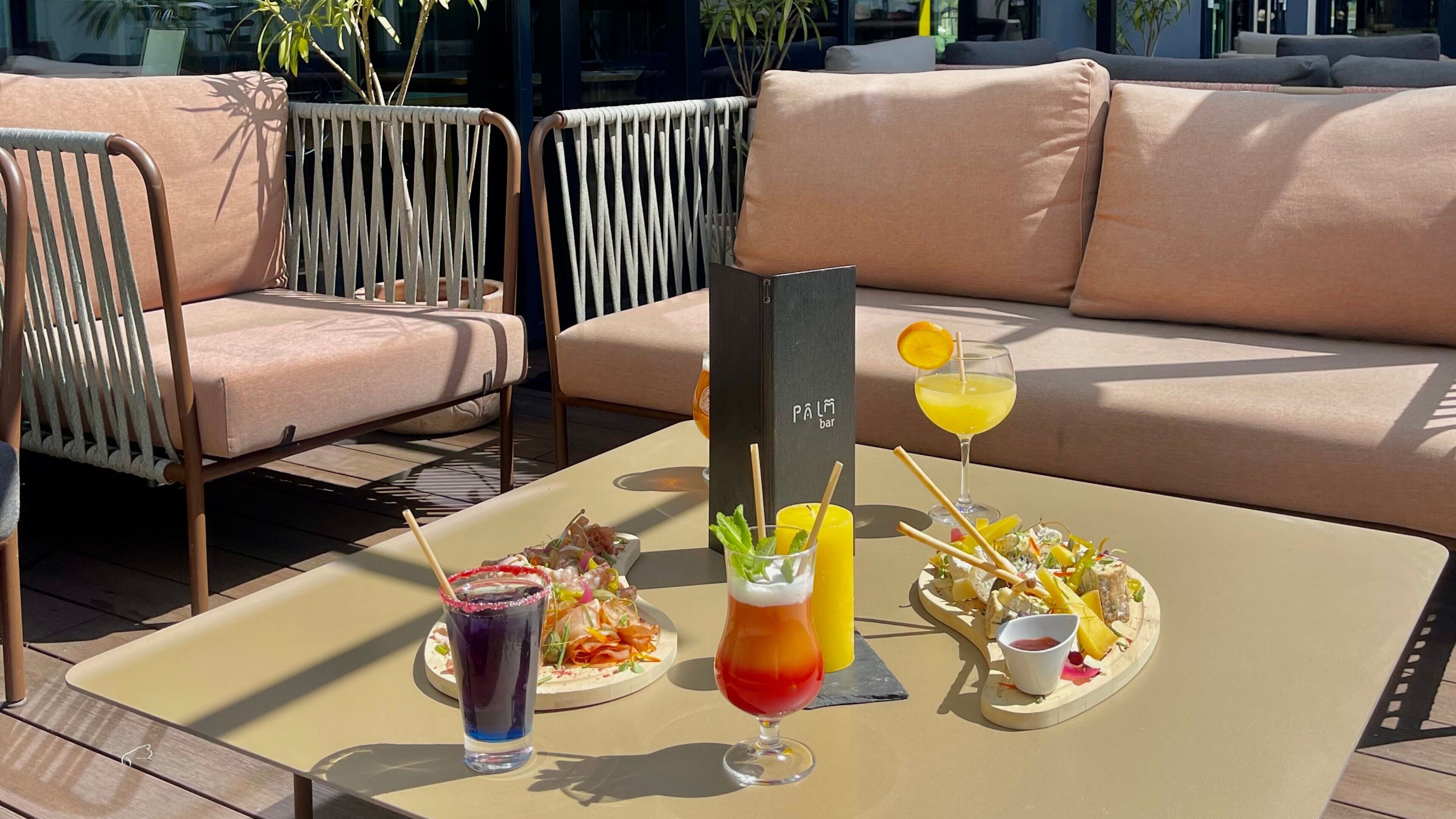 A table with drinks and a plate of food, a bar sign, and outdoor seating.