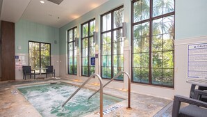 Un espace spa comprenant un bain à remous, des sièges et de grandes fenêtres.