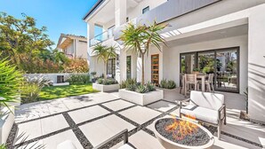A modern house with a patio area featuring a fire pit, outdoor seating, and a well-maintained garden. - Luxury 4Bedroom home only 2 blocks from the beach! (Newport Beach)