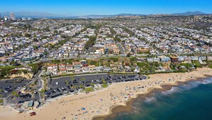 An aerial view of a coastal city with a wide beach, residential areas, and a clear view of the ocean. - Luxury 4Bedroom home only 2 blocks from the beach! (Newport Beach)