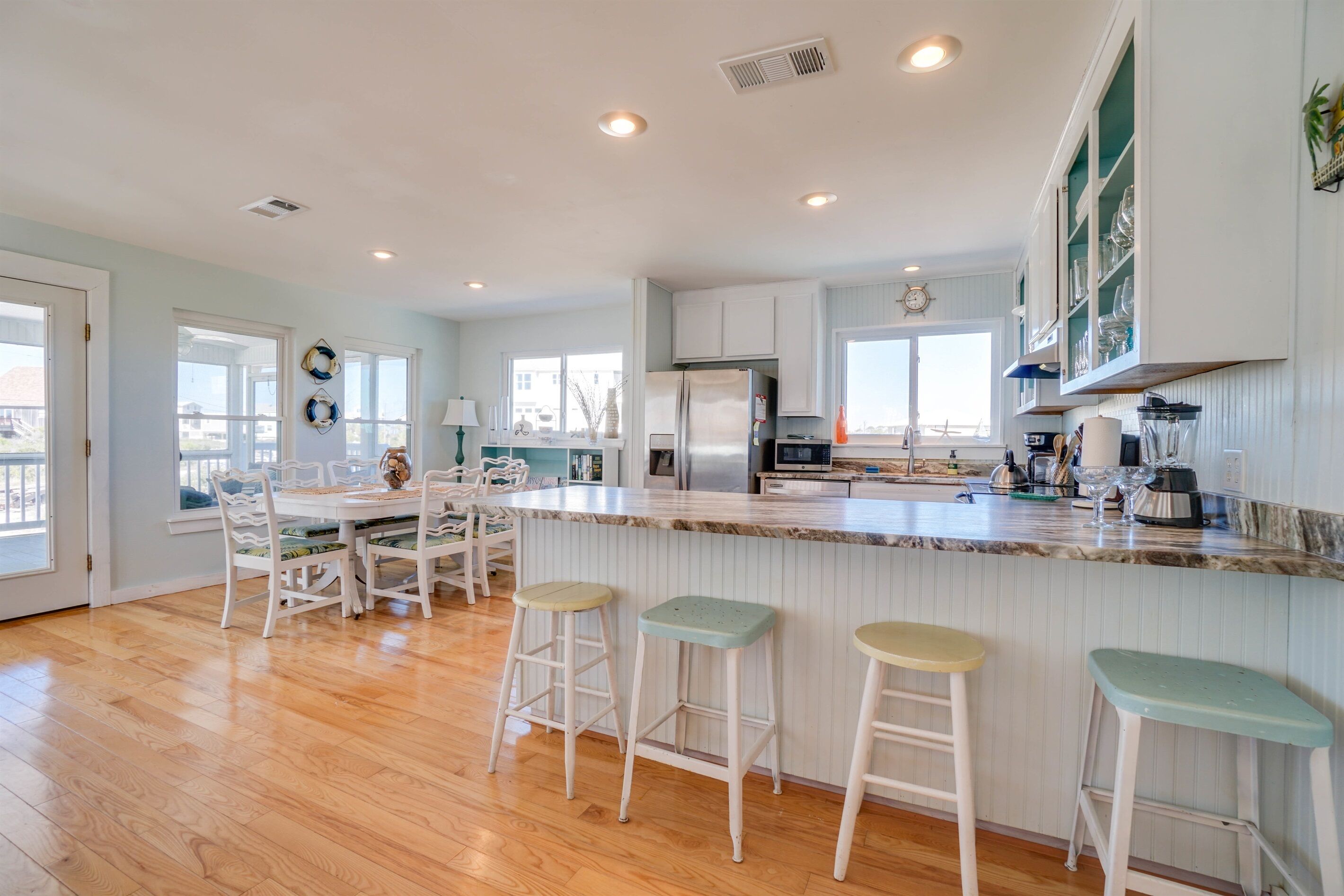 Una cocina amplia con una isla grande, muebles blancos y vistas al exterior.