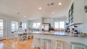 Un'ampia cucina con un'isola grande, mobili bianchi e vista sull'esterno.