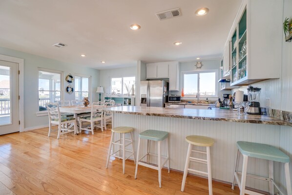 A spacious kitchen with a large island, white cabinetry, and a view of the outdoors.