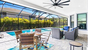 An outdoor patio with a pool, wicker furniture, and a ceiling fan.