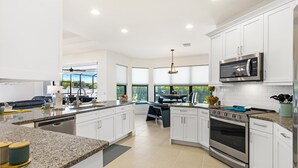 A modern kitchen with white cabinets, granite countertops, a built-in microwave, and an oven.