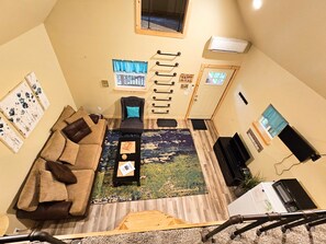 A compact living space with a sofa, coffee table, and a small rug. There are wall-mounted hooks and a door with a window.