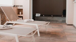 A wellness room with a fireplace, two lounge chairs, and a small table. - Principe Alogna Wellness & Spa (Altavilla Milicia)