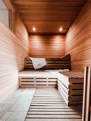 Un sauna aux murs et aux bancs en bois, une serviette suspendue à un banc et une petite table avec une autre serviette.