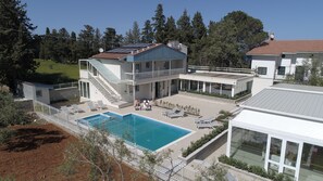 A modern two-story house with a swimming pool, a covered patio, and a large garden.