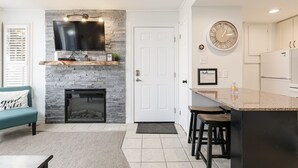 Una cocina moderna con protector mural de piedra, televisor integrado y un reloj de pared redondo.