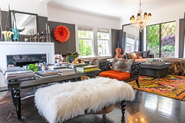 A modern living room with a fireplace, books, a sofa, and a large window. - CASABLANCA- Grand Edwardian View Home (San Francisco)
