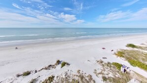 Une plage avec un ciel dégagé, un rivage sablonneux et une végétation clairsemée.