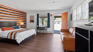 A modern bedroom with a bed, a desk, and a leather sofa. - Wagon Wheel Motel (Saco)