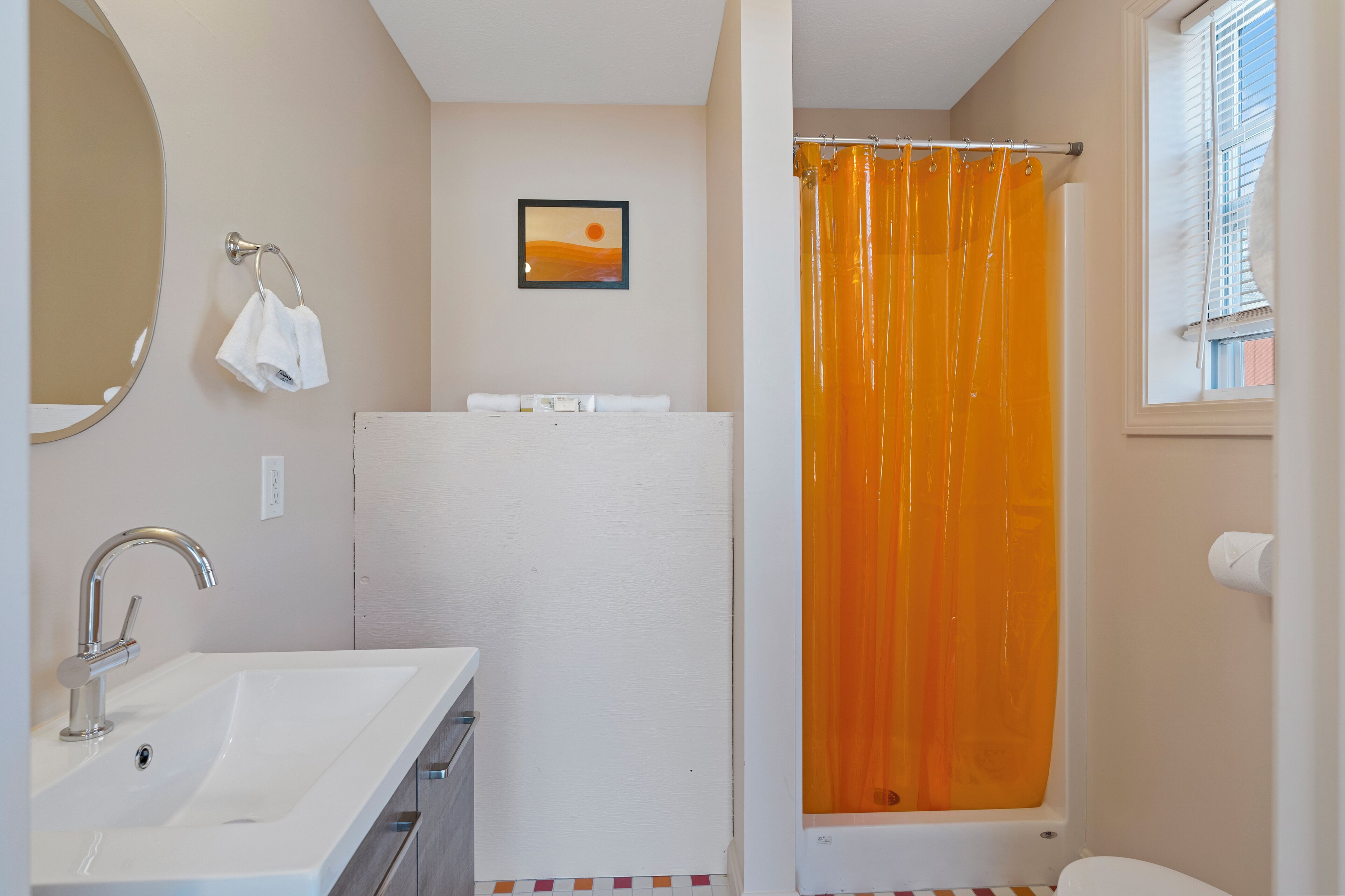 A bathroom with a white sink, a shower curtain, and a framed picture on the wall.