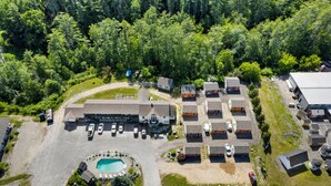 An aerial view of a residential area with a large building, multiple houses, a swimming pool, and a parking lot. - Wagon Wheel Motel (Saco)