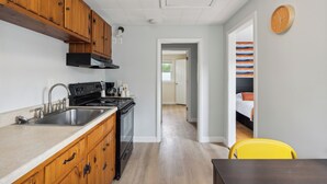 A kitchen with wooden cabinets, a black stove, and a stainless steel sink. - Wagon Wheel Motel (Saco)