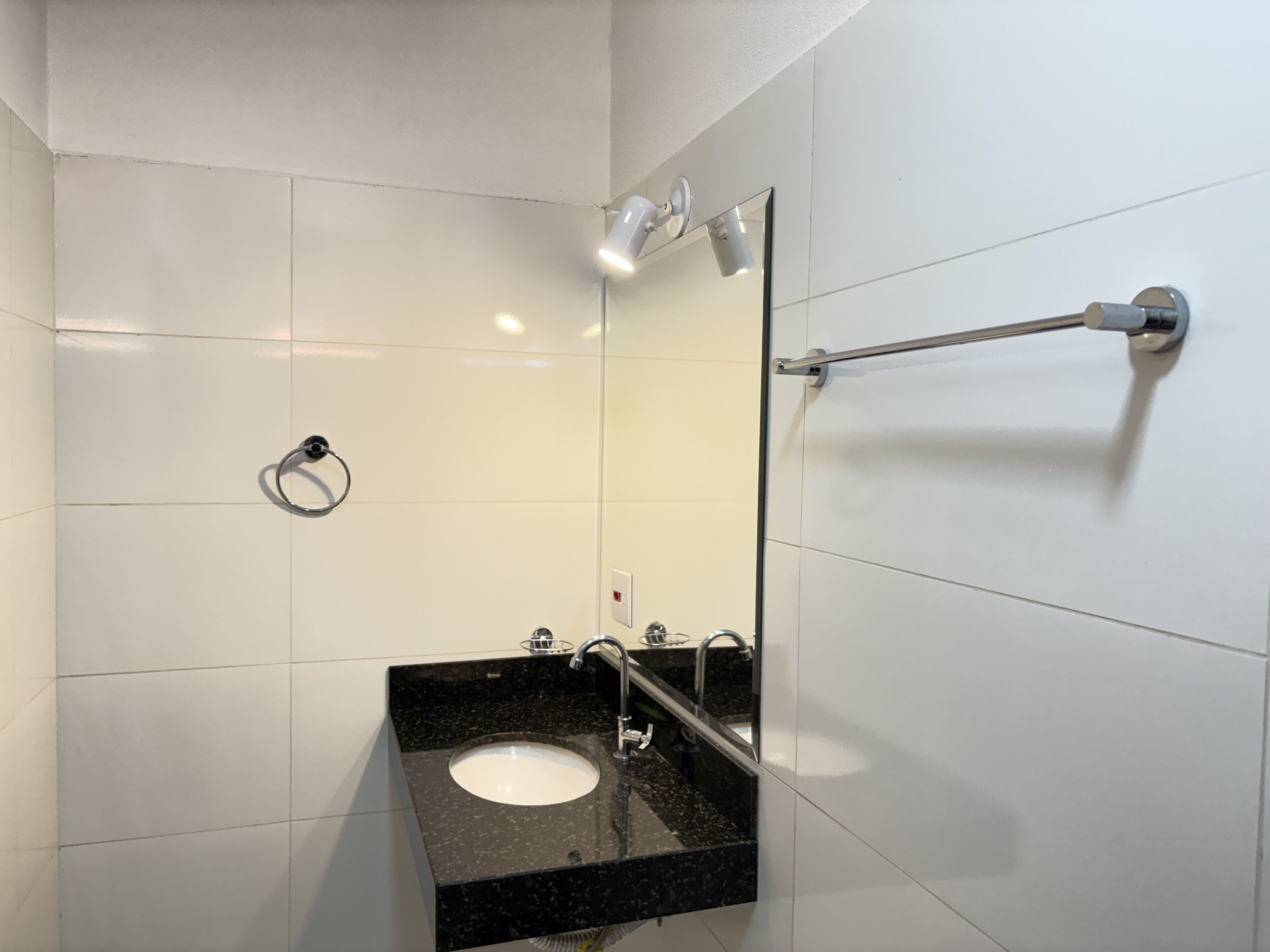 Casa de banho moderna com lavatório de granito preto, espelho e porta-toalhas.