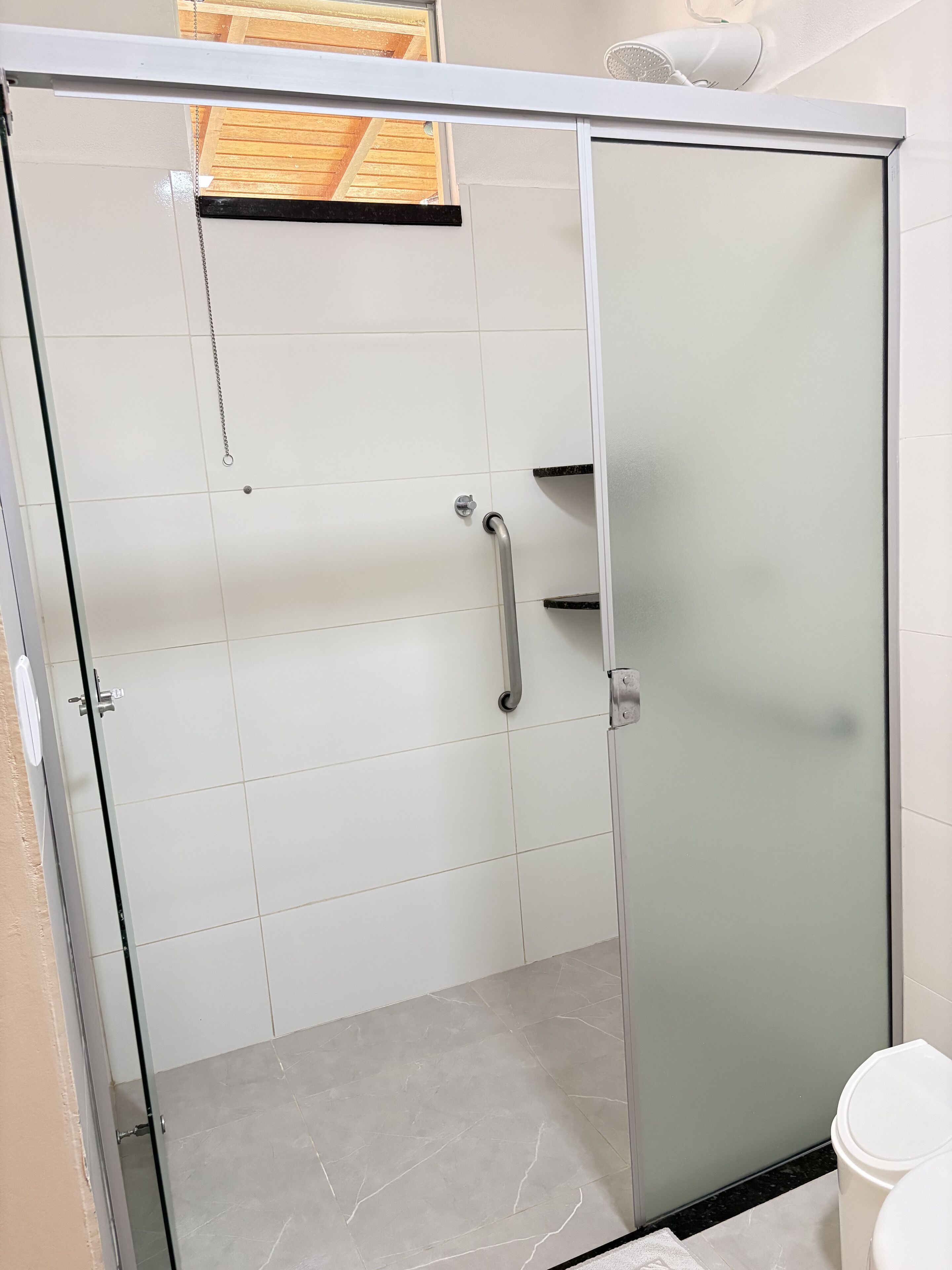 A bathroom with a glass shower enclosure, a toilet, and a sink.