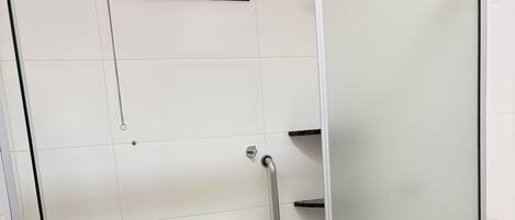 A bathroom with a glass shower enclosure, a toilet, and a sink.
