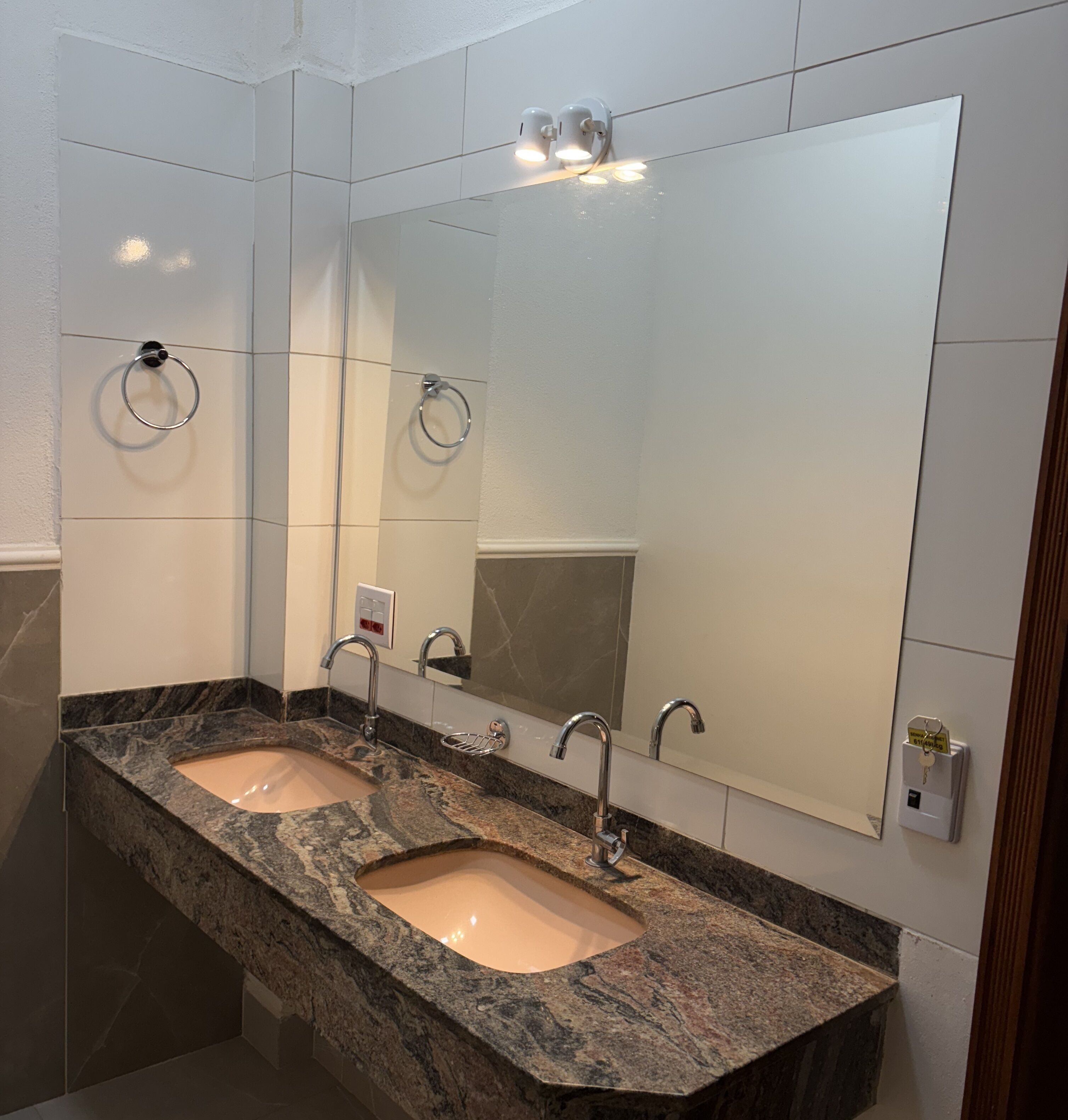A modern bathroom with two sinks, a large mirror, and a towel ring.