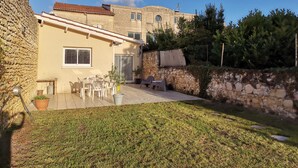 Una casa de piedra con techo de tejas, un patio con mobiliario exterior y una pared de piedra.