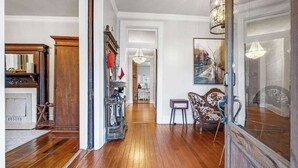 A spacious hallway with wooden flooring, a vintage radio, and a dining area with a patterned table and chairs. - Downtown Private Backyard Oasis 5 min to Broadway (Nashville)