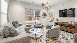 A modern living room with a sofa, armchairs, a coffee table, and a TV. - Downtown Private Backyard Oasis 5 min to Broadway (Nashville)