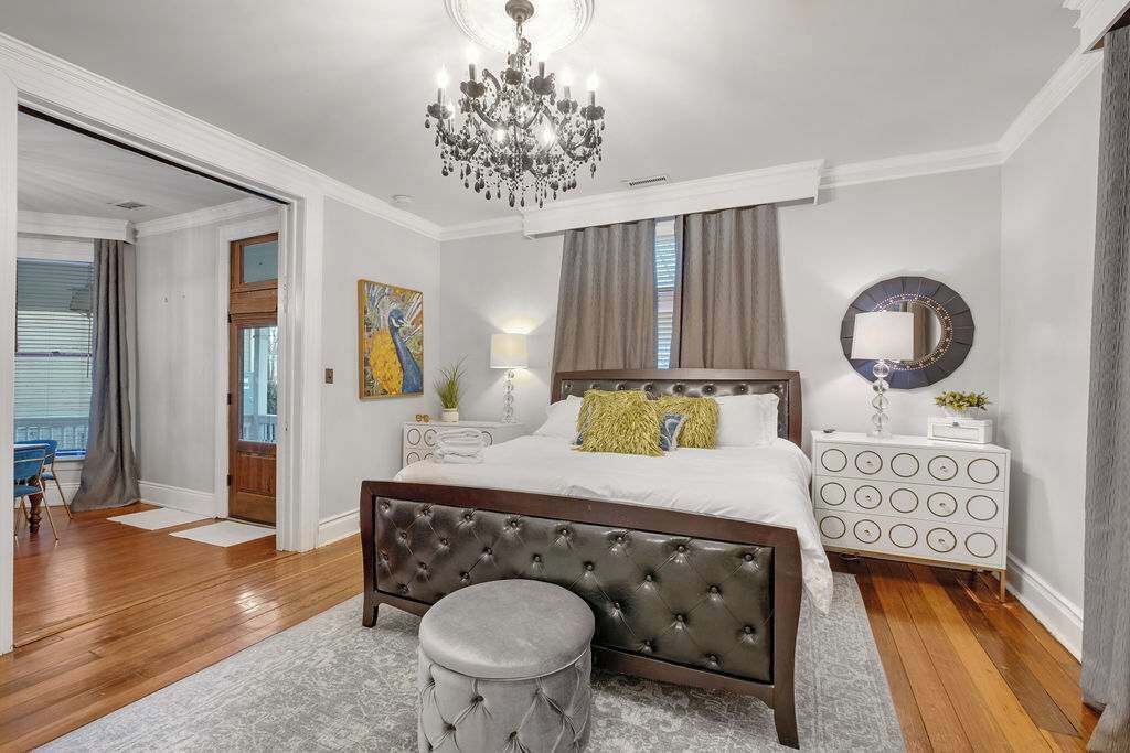 Une chambre à coucher avec un grand lit, un lustre, un miroir rond et une table de chevet.