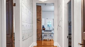 A hallway with wooden flooring, white walls, and a chandelier. - Downtown Private Backyard Oasis 5 min to Broadway (Nashville)