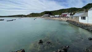 A coastal town with clear waters, boats, and a stone wall along the beach.