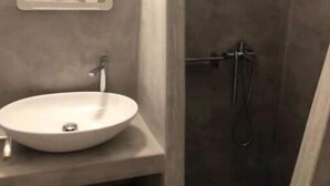 A bathroom with a round sink, a mirror, and a shower area. - Sunset Villa II (Paros)