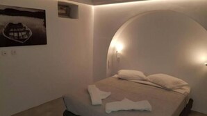 A modern bedroom with a bed, a wall-mounted light, and a painting. - Sunset Villa II (Paros)